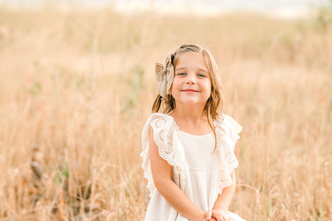 Girl smiling into camera during fall family photos by Flying Gull Photography