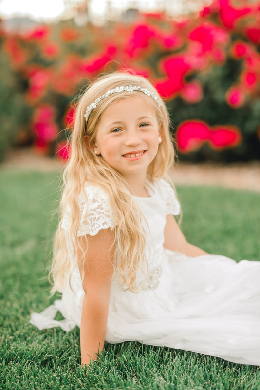 8-year-old girl in baptism dress with roses behind her