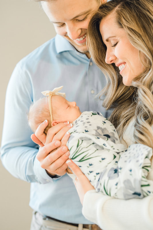 mom and dad smile at baby in Provo white studio