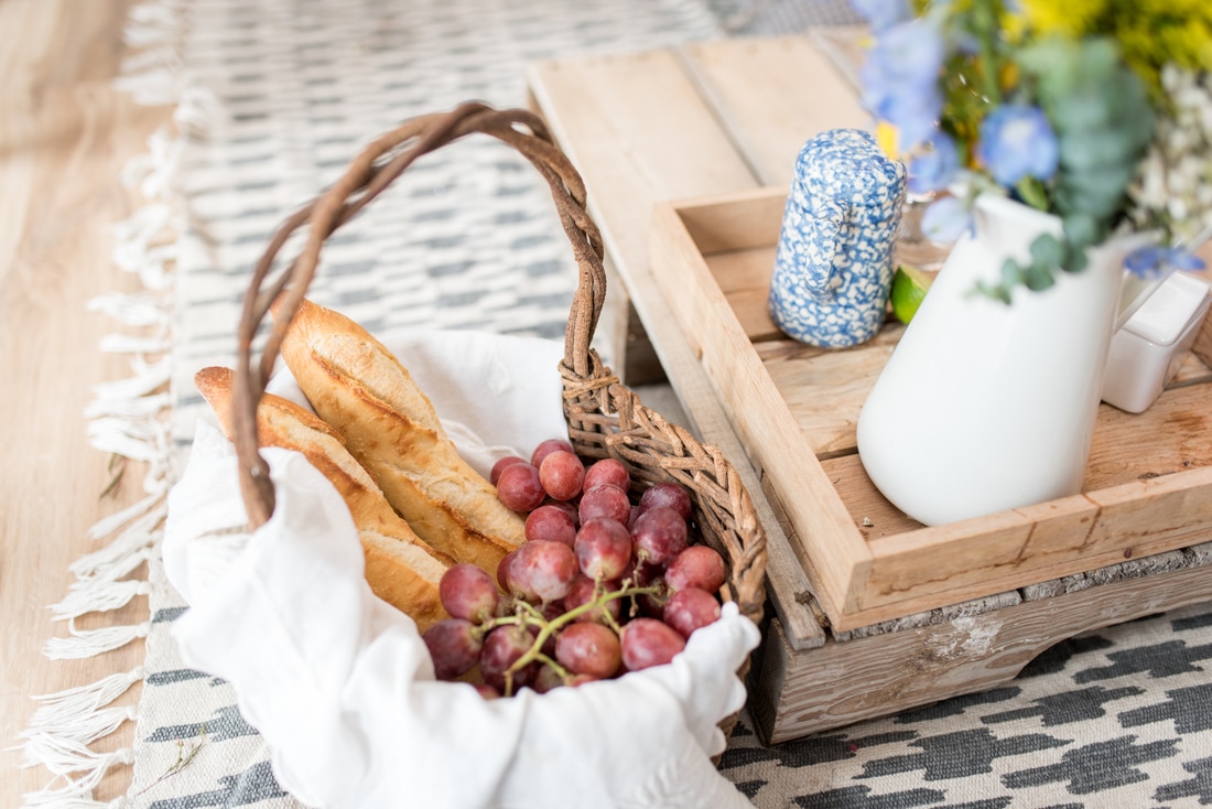 Picnic setting from boho styled wedding shoot includes blue and white china, french bread, and other rustic items.