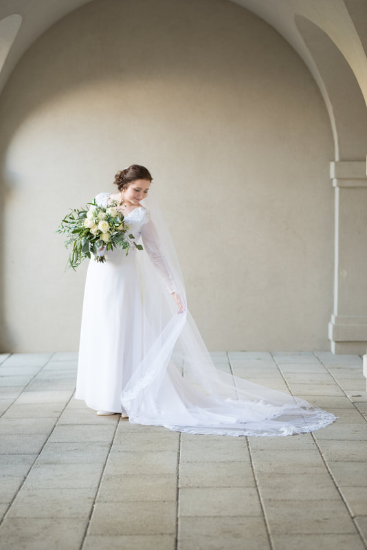 Bride ruffles cathedral veil in full-length portrait