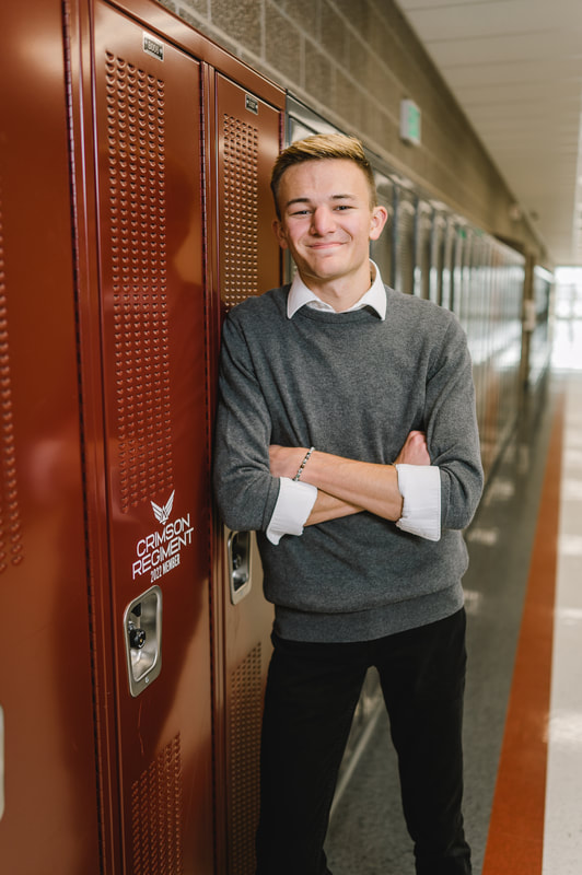 Senior boy leans against high school lockers