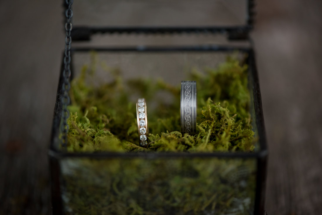 Bride and Groom's rings in a glass ring box with moss