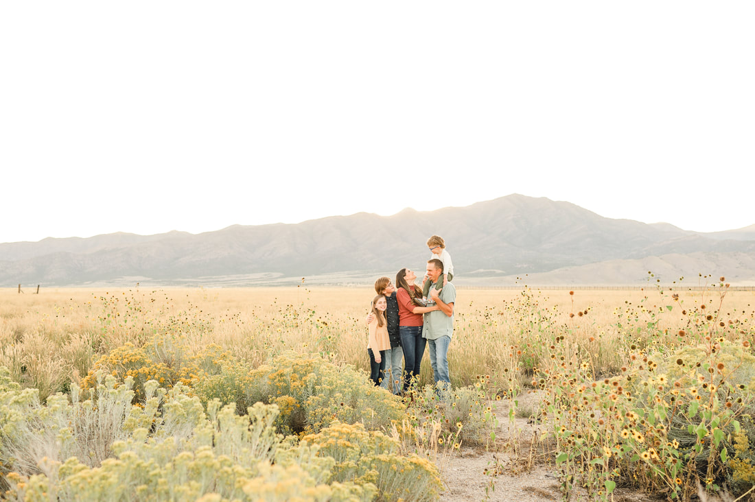 Family with three children standing in a field of wheat and sunflowers in Eagle Mountain Utah at sunset.