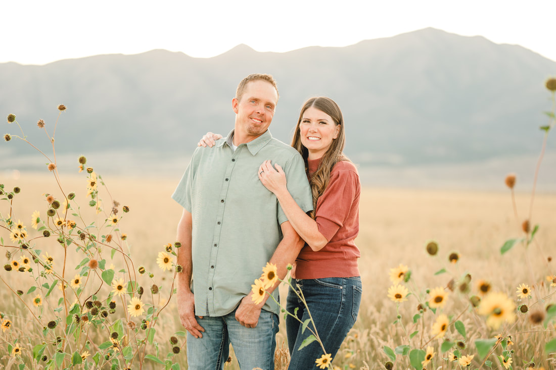 Sunset couple photos in Utah. Husband and wife standing in a field of flowers.