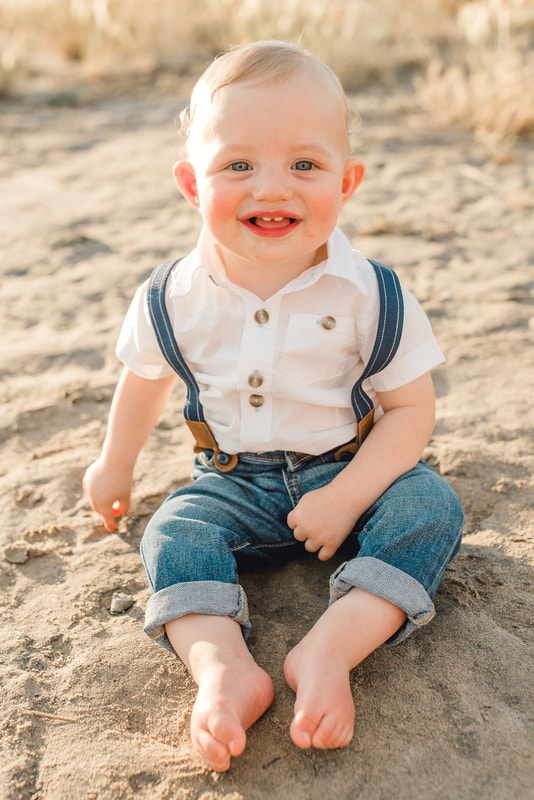 Baby boy in suspenders, white shirt and denim on beach in Utah
