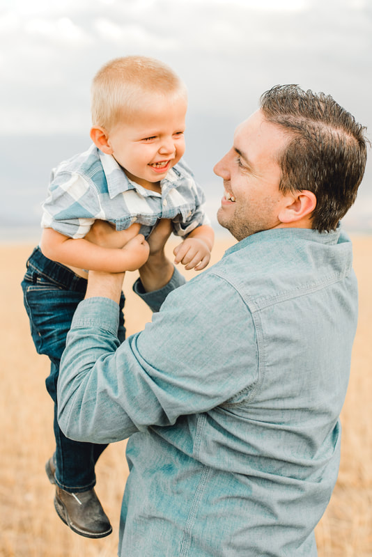 Dad playing with son in wheat field in Utah