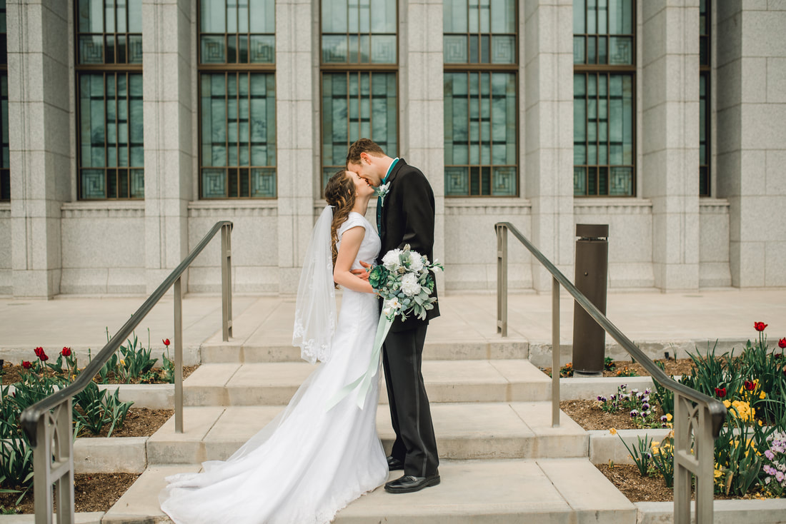 Bride and groom kiss in front of the stained glass windows in Draper Utah