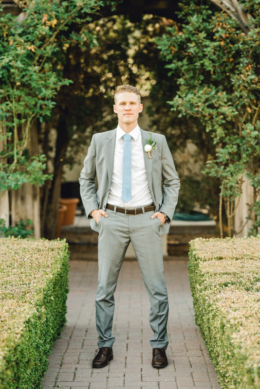 Groom portrait surrounded by hedges and climbing roses