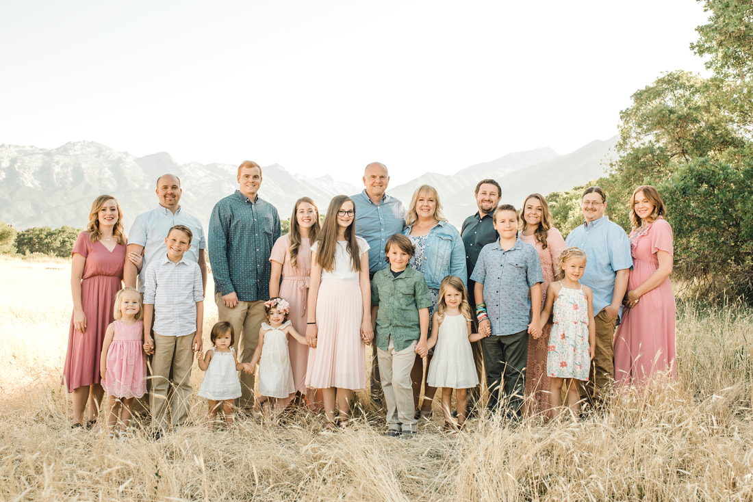 Family photo in a field with Utah mountains behind