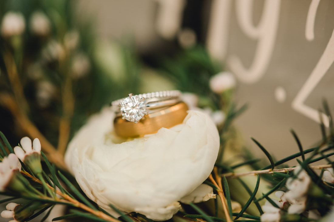 Gold mens band and women's solitaire ring shot Utah wedding