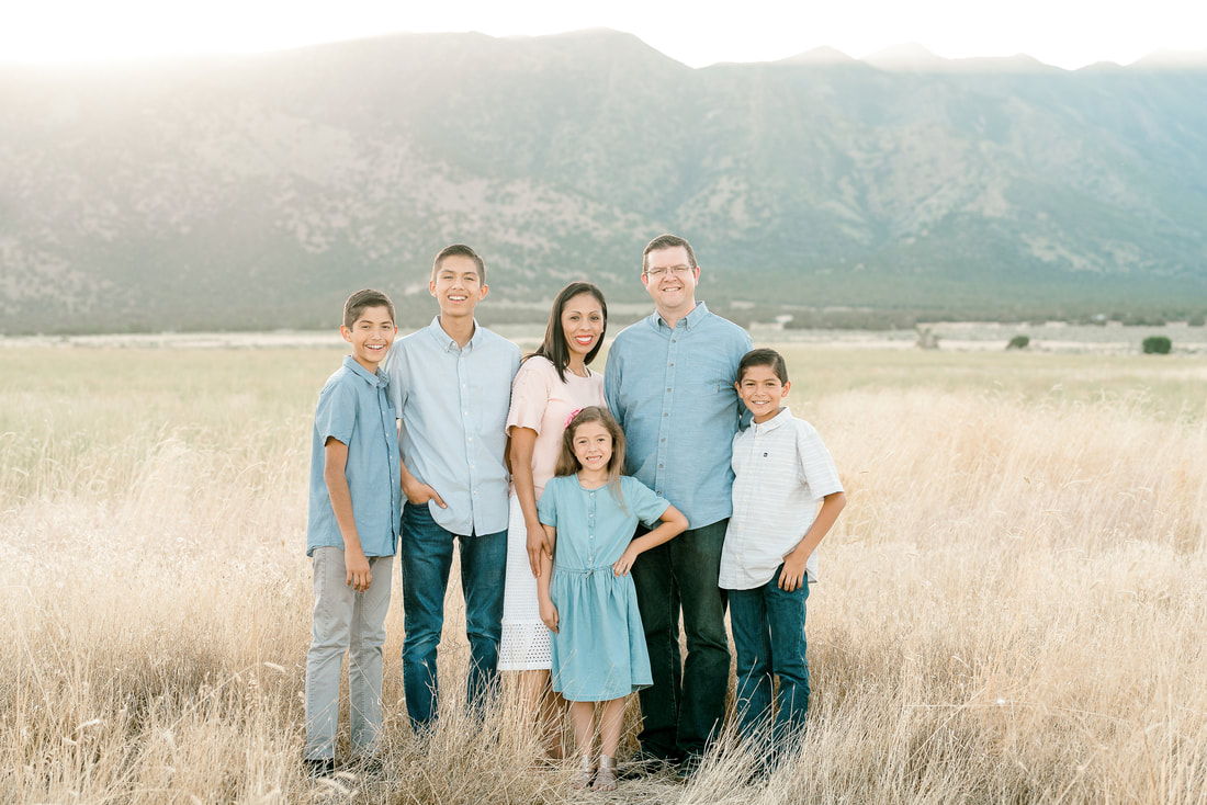Single family with mom, dad, and 4 kids in golden field with utah mountains at sunset