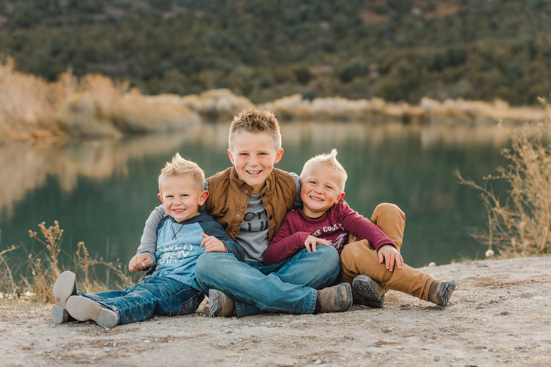 Three brothers sitting in front of a lake in Utah