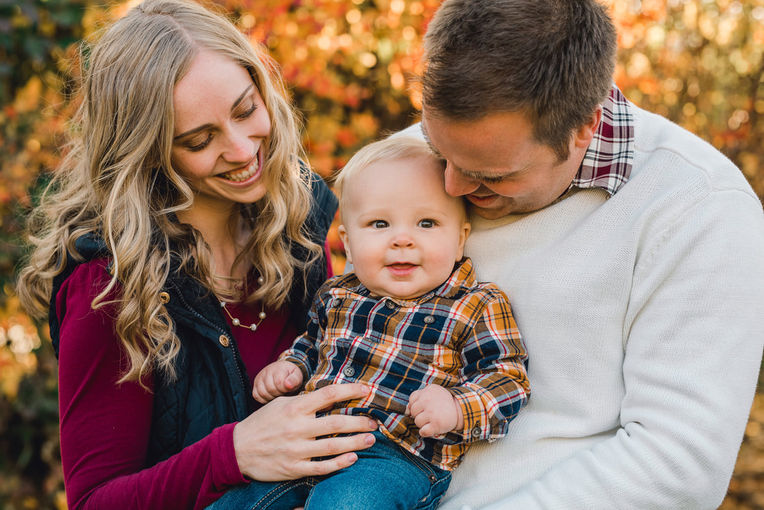 Parents smile down at a toddler in their arms during family photos in Utah