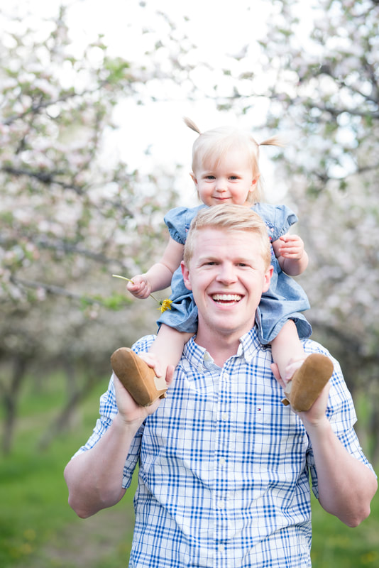 Baby girl on dad's shoulders in Provo apple orchard