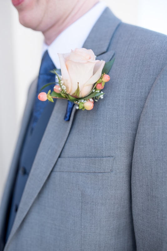 Detail shot of groom's peach rose boutonniere