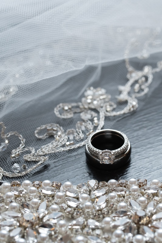 Detail shots of wedding rings, bride's sash, and veil edge with glass beads