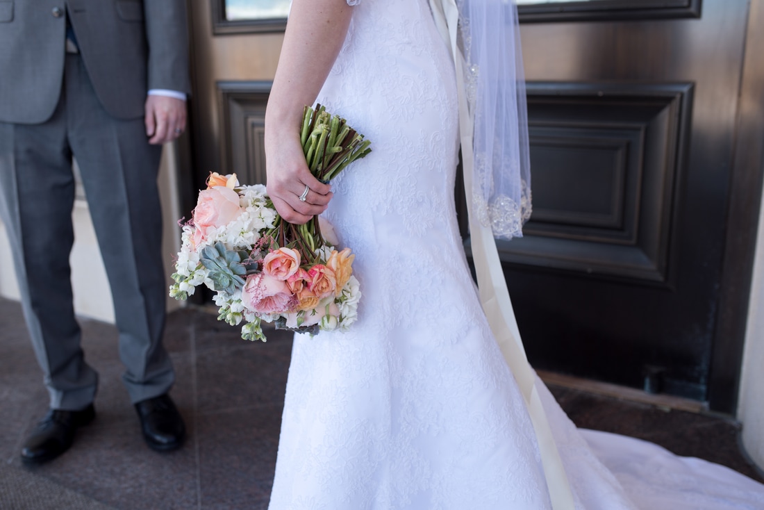 Photo of bride's hand holding bouquet and showcasing diamond ring