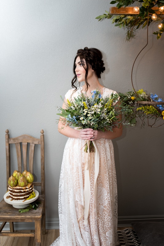 Boho wedding with bride in peach lace dress, blue and yellow wildflowers, naked cake with pears and caramel