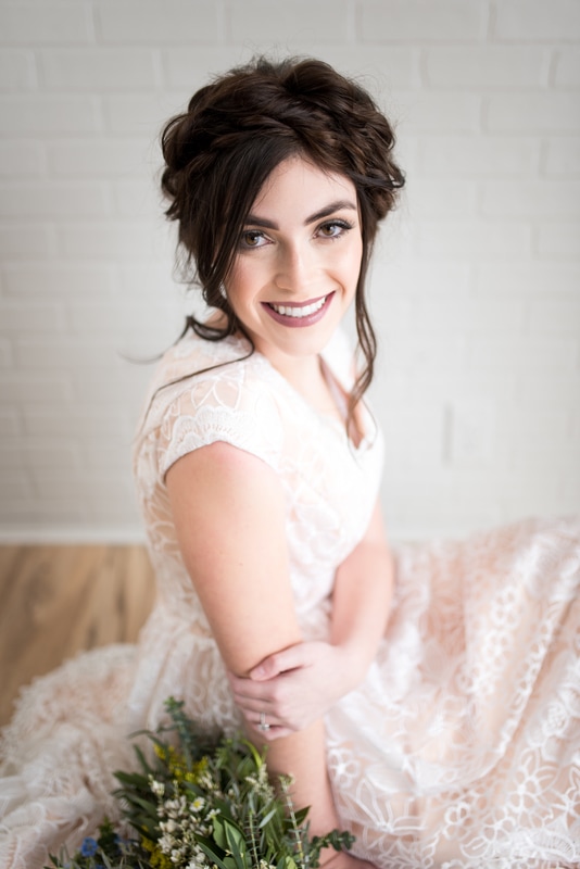 Beautiful young bride in peach lace wedding gown smiles.