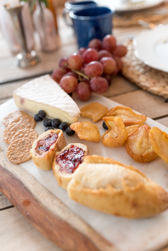 Rustic board filled with crusty breads, crackers, jam, etc.