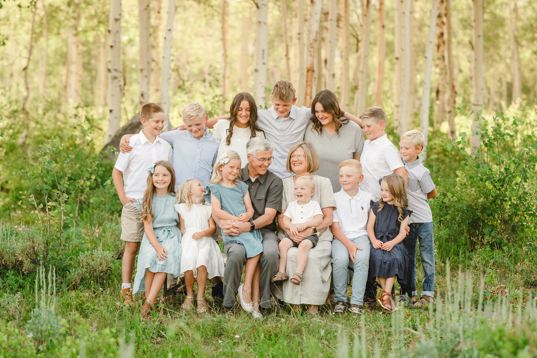 Grandparents surrounded by grandchildren in Utah mountains with aspens and wildflowers