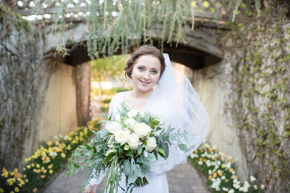 Bride under bridge with flowers lining walkway