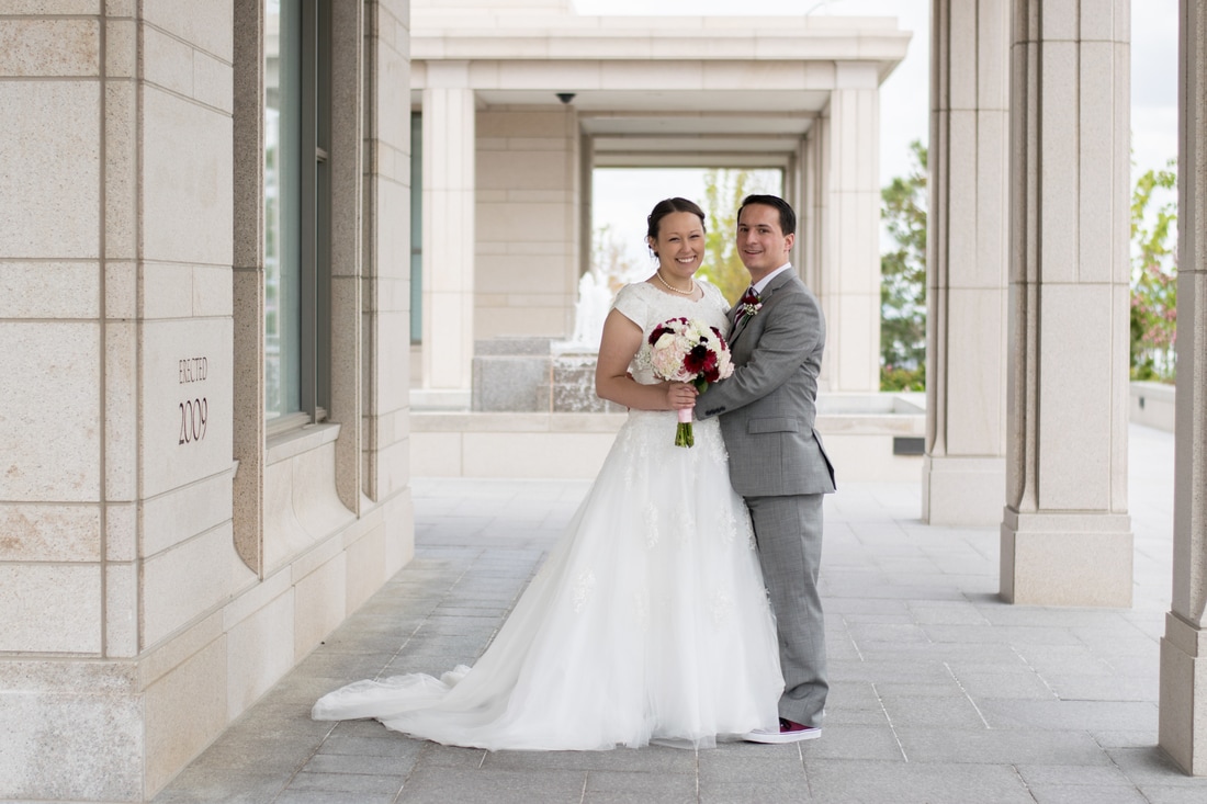 Photo of bride and groom in grey suit in front of Oquirrh LDS Temple